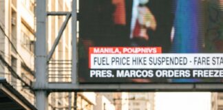 Marcos Suspends Fare Hikes Amid Rising Fuel Costs in the Philippines: What Commuters Need to Know Commuters queue beside jeepneys on a Manila street beneath a news screen announcing a suspended fare hike