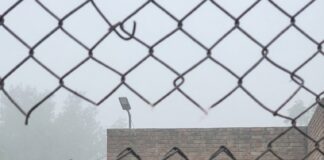 Seven Foreigners Arrested in India on Charges of Training Myanmar Rebels and Drone Smuggling Police officers hold several detained men in a compound behind a chain-link fence, a seized drone on the ground