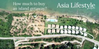Aerial view of a row of identical villas along a cleared coastal hillside, with a swimming pool near the shoreline