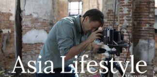 A photographer bends over a large-format camera on a tripod inside a derelict brick building