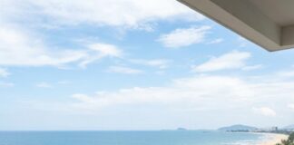 Best Cities for Digital Nomads in Asia 2026: Your Ultimate Guide to Remote Work Destinations A man in a straw hat works on a laptop at a balcony bar overlooking a Vietnamese beach