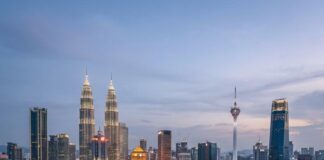 Night view of the Kuala Lumpur skyline with the Petronas Towers and KL Tower lit above the surrounding neighbourhoods