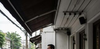 Dining Dilemmas: Unpacking the Challenges Facing Asia’s Culinary Scene A restaurant worker in an apron stands outside his shuttered shopfront in the rain beside an Open for Songkran sign