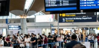 A check-in agent holds up two passports for a traveller at Kuala Lumpur International Airport