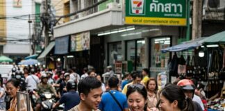 Tourists choose dishes at a Bangkok street-food stall as the cook works a wok in the foreground