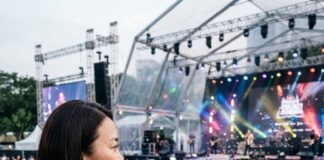 KL’s Dazzling Rise in the Regional Entertainment Scene An executive watches a crowded outdoor concert from a viewing platform beside a Kuala Lumpur entertainment hub sign