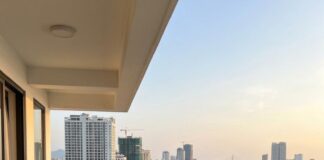 A man looks out from a high apartment balcony over Da Nang's beachfront road and the Dragon Bridge