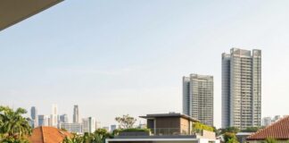 A family walks up the drive of a modern detached house in Singapore, the city skyline beyond the trees