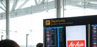 “Revitalizing Adventure: Unveiling the Regional Tourism Network Proposal” A traveller watches the departures board at Bangkok Suvarnabhumi Airport beside an AirAsia advertising screen