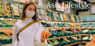 A woman in a face mask holds a grapefruit in a supermarket produce aisle during the Covid-19 pandemic