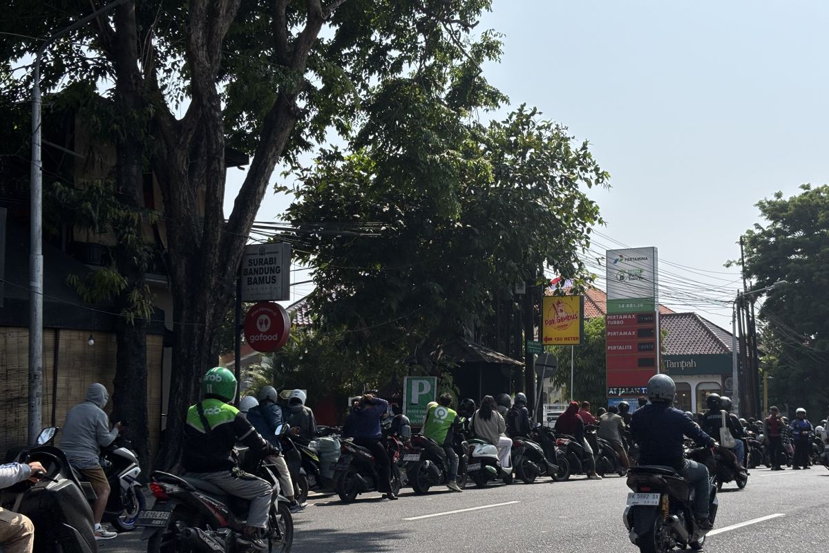 Riders queue along a road in Renon, Denpasar, waiting to refuel