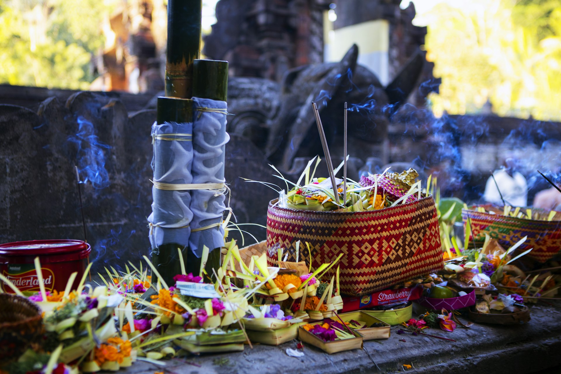 Canang sari palm leaf offering filled with red, yellow and green flowers in Bali