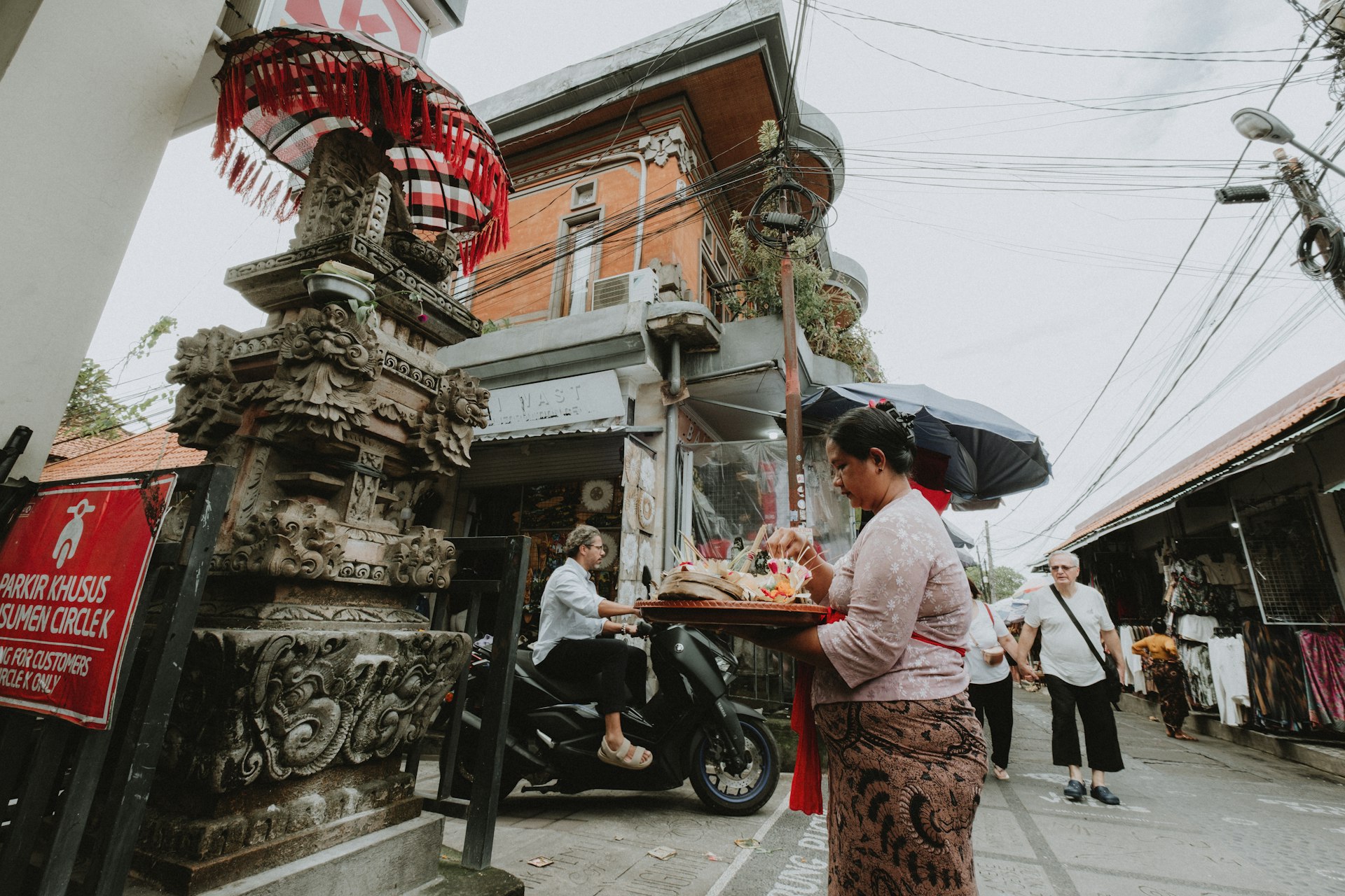 Balinese woman carrying offerings in front of an ornate temple entrance in Bali