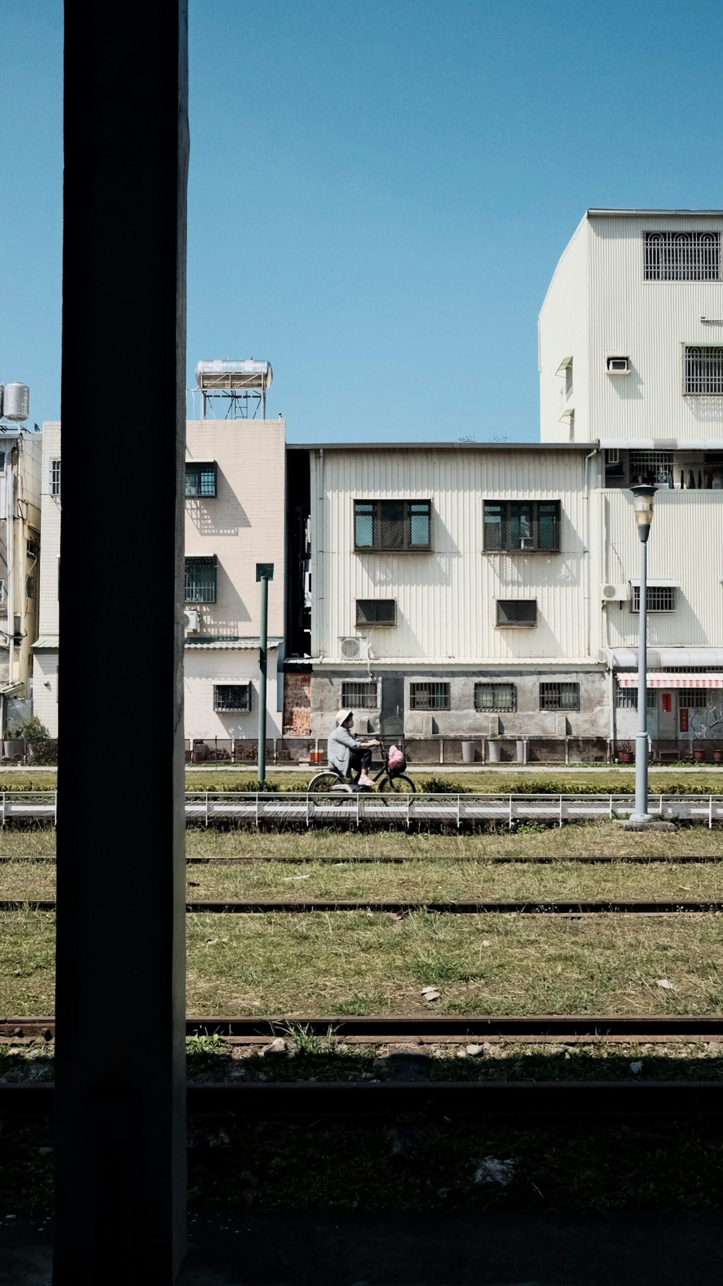 A cyclist rides past buildings beside a railway line in Taiwan