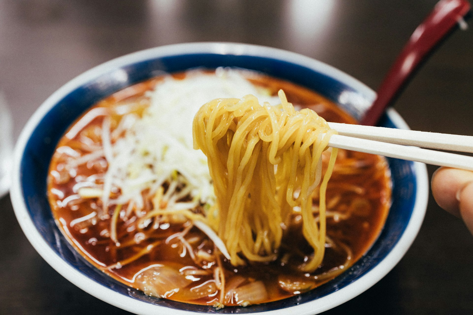 Diner holding chopsticks over a bowl of Japanese noodles