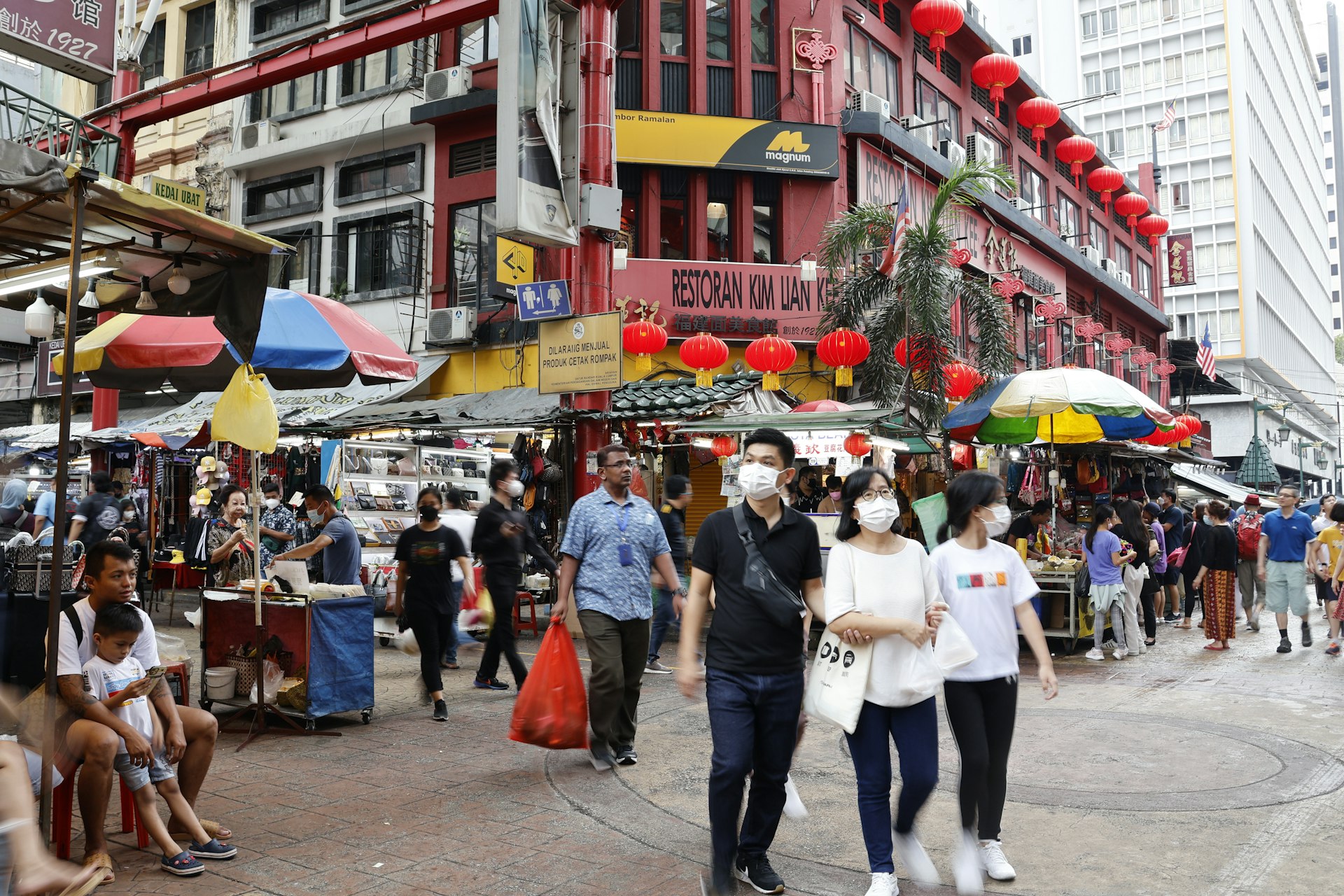 People walking down a street lined with tall buildings in Kuala Lumpur, Malaysia