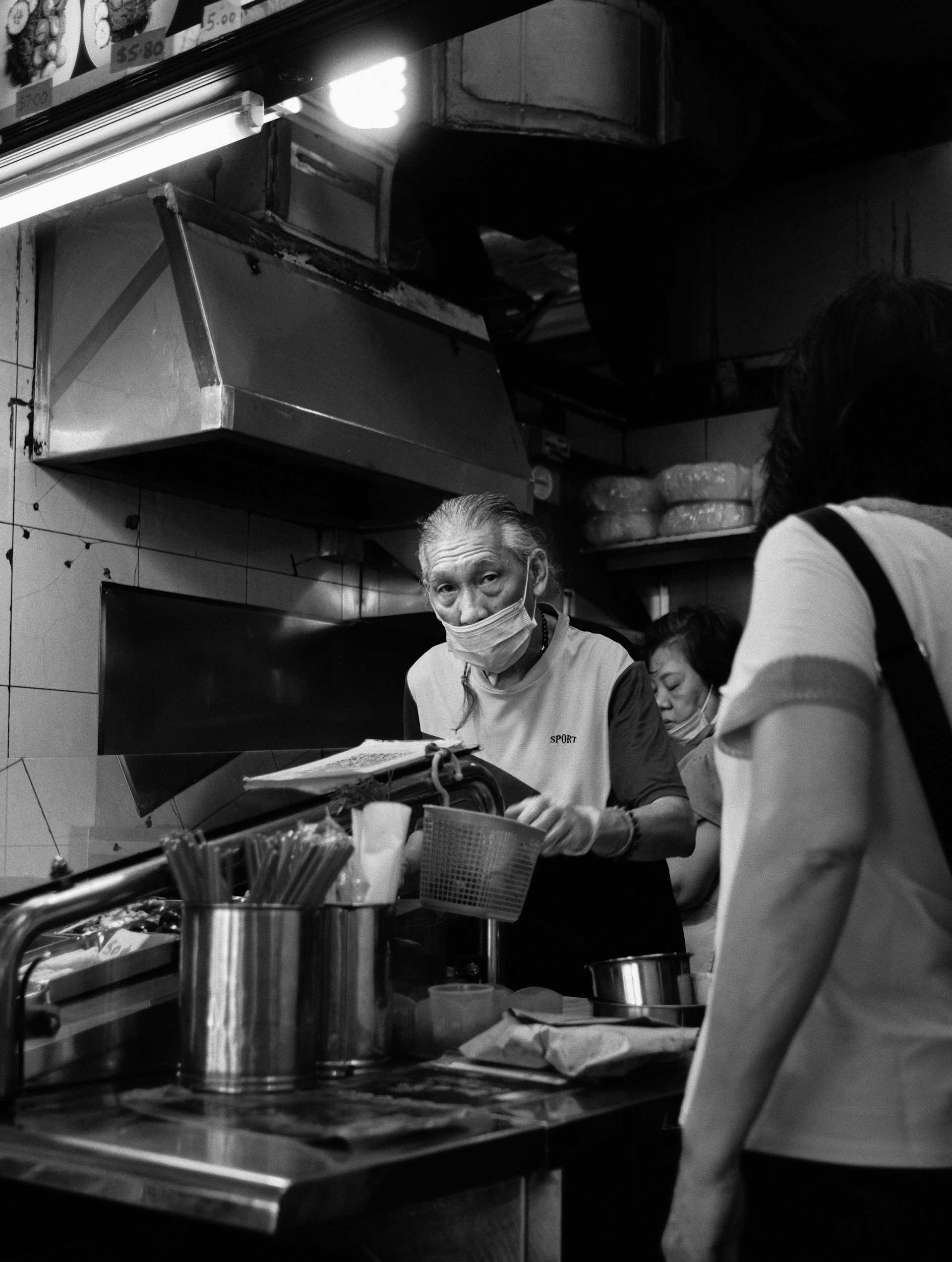 Hawker cook preparing food at a busy stall kitchen in Singapore