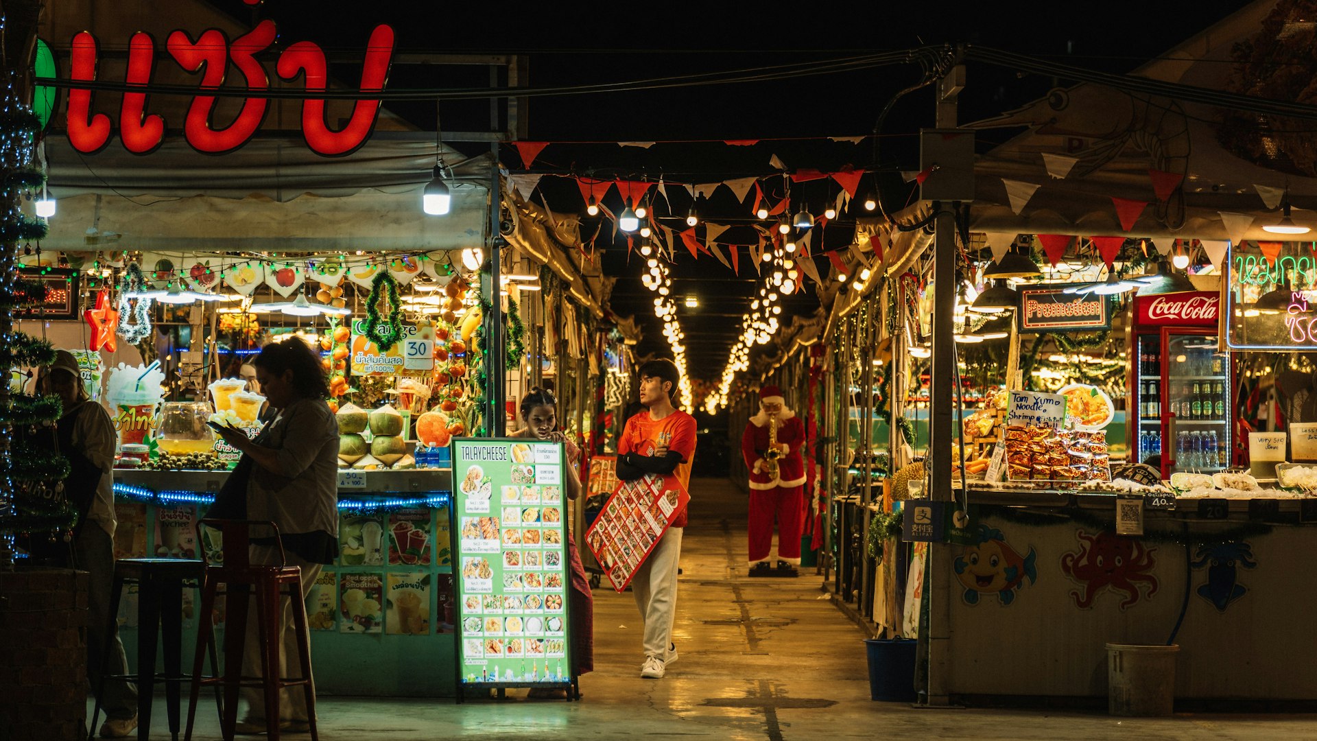 Shoppers at lit market stalls in the evening