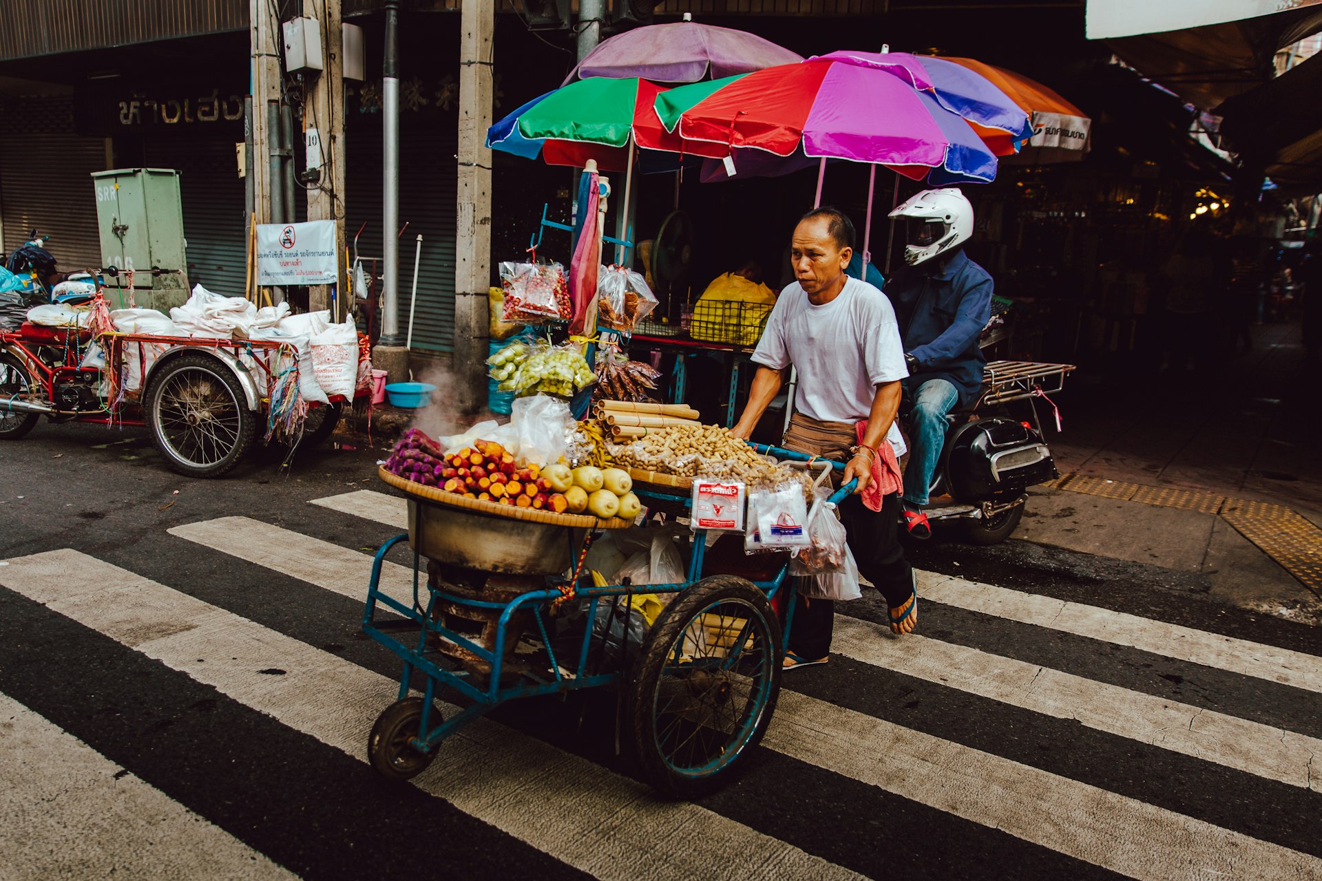 Thai man pushing his food cart along a pavement in Thailand