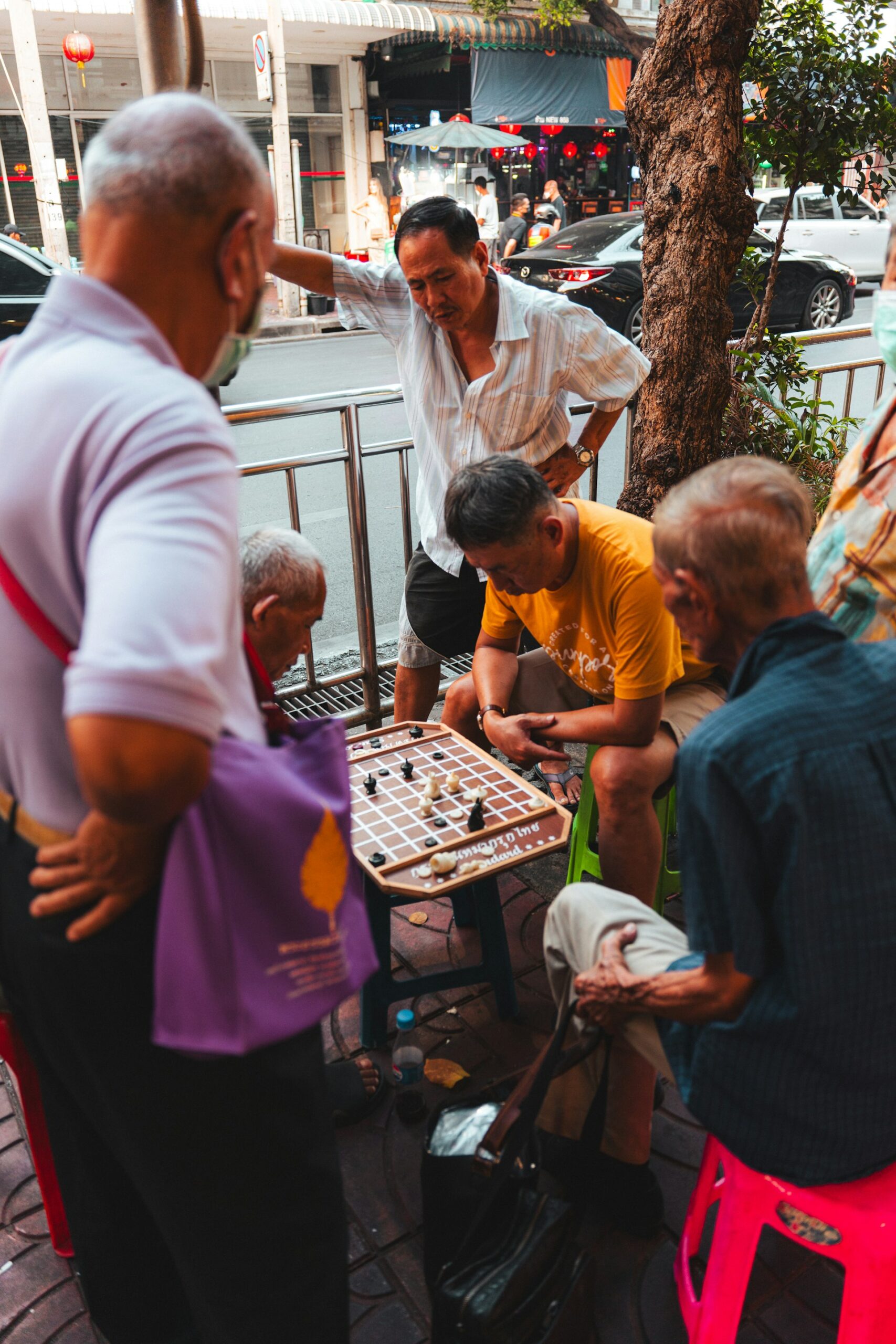 Group of men playing a board game together on a sidewalk in Bangkok